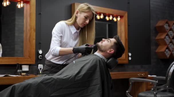 男人在理发店的椅子上放松下来 得到了仪容整洁的服务 专业理发师在现代沙龙里理发时尚 修剪胡子 理发师使用剪子 男性客户的工具 时尚的外观 — 图库视频影像