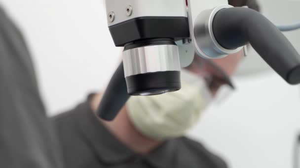 Zbliżenie Męskiego Stomatologa Asystentem Przy Użyciu Mikroskopu Stomatologicznego Podczas Operacji — Wideo stockowe