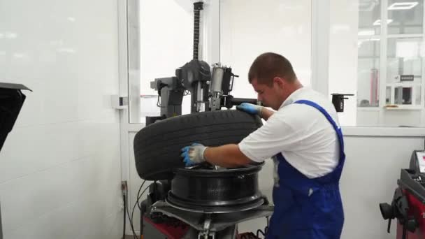 专业人员取出轮毂进行季节性更换 汽车修理工在车库里操作轮胎转换器 穿着制服的工人 安全手套换轮胎 汽车维修服务 车辆维修 — 图库视频影像