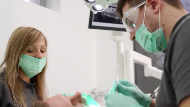 在治疗病人根管的过程中 使用牙科器械近距离拍摄男性牙医和女性助理 口腔科医生 现代牙科诊所团队合作期间的护士 内窥镜 — 图库视频影像