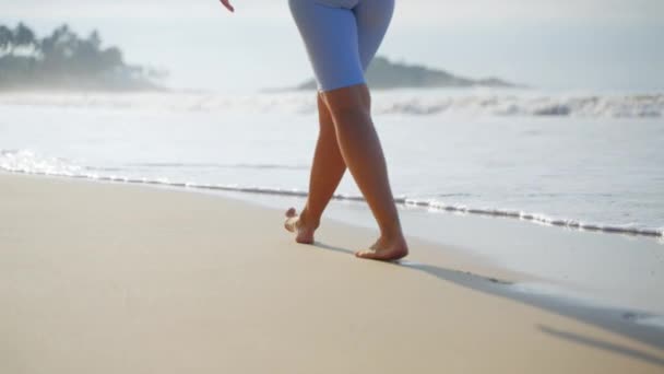 清静的清晨海滩漫步 宁静的活动为健康 赤脚人沿着海岸线行走 波浪轻柔地抚摸着脚 专注于腿 出游的氛围 闲暇时 海上留神 — 图库视频影像