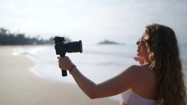 内容创造者拍摄海洋 棕榈树旅行日志 在热带海滩上 卷发妇女穿着白色比基尼记录了Dslr 游客平静的海滨 在日出时讲述数字故事 — 图库视频影像