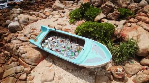 沿海垃圾场强调海洋污染问题的紧迫性 蓝色废船满载废弃塑料瓶及各类废物在岩石海滨倾泻的俯瞰图 — 图库视频影像