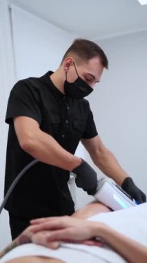 Teknolojik masaj aleti ile estetik vücut şekillendirme tedavisi. Erkek terapist, klinikte selülit, lenfatik drenaj masajı hedefleyen kadın hastalar üzerinde nihai terapi prosedürü uyguluyor..