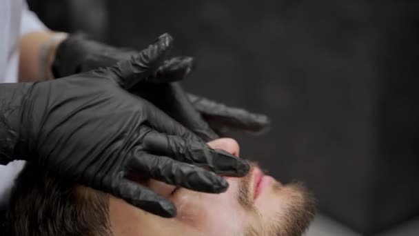 男性顾客享受护肤治疗 理发师在美容院为男人进行放松的面部按摩 专业服务 现代人健康的趋势 男性卫生 护理说明 — 图库视频影像