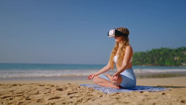 マインドフルなテクノロジーユーザーは静けさを発見し デジタルマインドフルネスリトリートに没頭します Vrヘッドセットの女性は ビーチで蓮のポーズに座り バーチャルリアリティで瞑想します 落ち着いたインタラクティブ体験の未来 — ストック動画