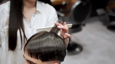 Islak saçlar üzerine dövmeli stilistin hassas makasları. Profesyonel berber kuaförde erkek müşteriye şık bir saç kesimi yapar. Modern pompadour şehir berber dükkanında hazırlanıyor. Tımarlama