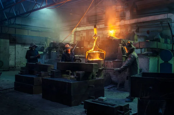 工业团队从事齿轮保护铸造 重工业制造 工人们把熔化的金属倒进钢厂 热金属锻造 团队合作 炉膛操作 图库图片