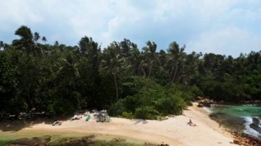 2023-03-15 - Mirissa Körfezi, Sri Lanka. Gizli sahil. Huzurlu sahil manzarası ziyaretçiler dinleniyor, tropikal palmiyeler sallanıyor berrak mavi sular yavaşça kumlu kıyıları sarıyor..