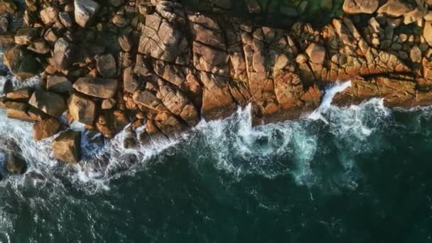 熱帯の海岸線に衝突する空の鮮やかな青い波 バードアイビューダイナミックな水の動き 泡によるパターン 岩に沿った深海ブルース 上から下の景色 スローモーション — ストック動画