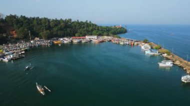 İnsansız hava aracı görüntüsü, Mirissa Limanı, Sri Lanka 'ya yanaşmış renkli balıkçı teknelerini yakalıyor. Balıkçılar, tropikal kıyıların yoğun bitki örtüsünün ortasında denize doğru hareketlenirken, Sri Lanka da hareketleniyor..