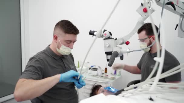 Dentysta Leczący Kanały Korzeniowe Mikroskopem Nowoczesnej Klinice Stomatologicznej Asystent Dentysty — Wideo stockowe