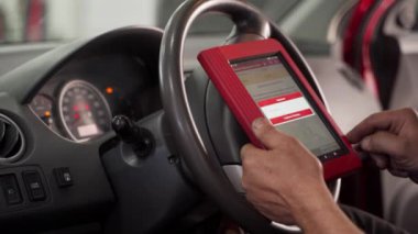 Uzman araç kontrollerini, atölyedeki fay kodlarını kontrol ediyor. Otomobil elektrikçisi araba sorunlarını teşhis etmek için OBD-II tarayıcı kullanıyor. Bakım, servis, tamir süreci gösterildi.
