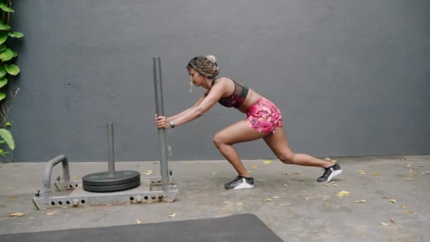女性注重减肥 通过锻炼 耐力来增强肌肉的力量 女运动员参加密集的交叉组合训练 在室外环境中推着沉重的雪橇 Slomo — 图库视频影像