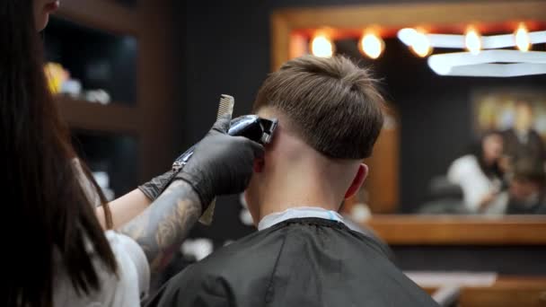 タトゥー付きのヘアスタイリストは男性クライアント フェードサイド トリムトップで動作します プロのバーバーは 現代の床屋で組み合わせ 電気クリッパーでスタイリッシュなヘアカットを提供します グルーミングセッション サロンインテリア — ストック動画
