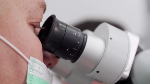 Zbliżenie Męskiego Naukowca Masce Medycznej Patrzącego Mikroskop Laboratorium Biotechnologicznym Wirusolog — Wideo stockowe