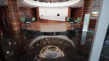 2022-01-18 - Famagusta, Kuzey Kıbrıs. Roman Merkezi Modern otel resepsiyon alanı, cilalı dekor, resepsiyonist asistanı, arka planda şirket yolcuları, görünür geniş bir dinlenme odası..