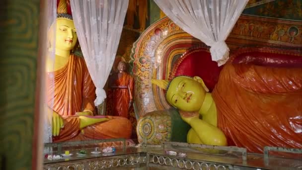 厳粛な平和的な雰囲気は 文化遺産 瞑想の実践を反映しています ブッダリクライニングの黄金の像は 装飾されたローブ 活気ある仏教寺院に座って 複雑な壁画に囲まれ 白いドレッピング — ストック動画