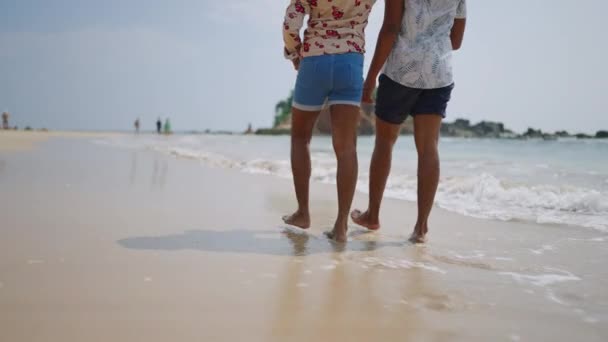 男人们喜欢休闲的休息 温暖的海风 在异国情调的目的地放松的步伐 这对同性恋夫妇手牵着手在阳光灿烂的海滩上散步 海浪轻柔地掠过赤脚 温馨祥和的假日 — 图库视频影像