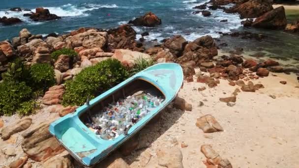空中的景色展现了一艘满载塑料瓶和垃圾的搁浅的船 一个废弃沙滩上的临时垃圾箱凸显了海洋污染和回收利用的紧迫问题 — 图库视频影像