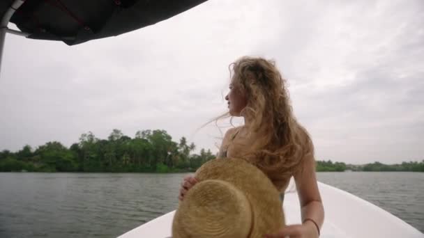 わら帽子をかぶったソロ旅行者は 弓に手を伸ばし 熱帯の風を救う カーリーヘアの女性は 船で川ツアーを楽しんでおり 緑豊かな緑を観察しています アドベントロウスの女性は 水の探検に野生生物の景色を求めています — ストック動画
