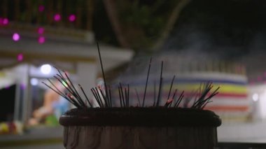 Kırmızı közler, kültürel tören sırasında gece dumanlar yükselir. Budist tapınağındaki parlak tütsü çubuklarının yakın çekimi. Dindarlarla dolu yumuşak ışıklandırmalı tapınma alanının arka planı. Asya 'da barışçıl ruhsal uygulama.