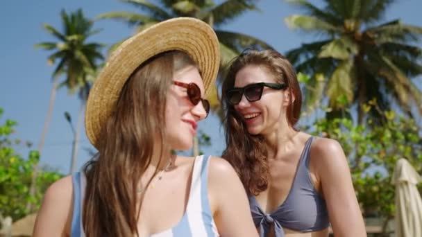 快乐的年轻女人帮助朋友在热带海滩涂防晒霜 快乐的女孩冷 晒黑在天堂岛上 棕榈树 女性朋友用防晒霜 后续行动 — 图库视频影像