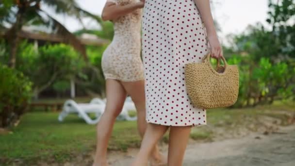 晴れた日 エキゾチックな緑の植物のトロピカルビーチに行くドレスでスリムな女性の足 二人の若い女性が話し 散歩で笑った 夏休みで一緒に旅行する魅力的な女性 — ストック動画