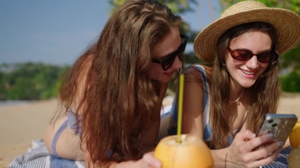 Meninas Felizes Deitadas Sol Navegando Nas Mídias Sociais Telefones Praia — Vídeo de Stock