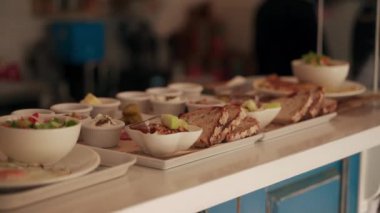 Kafe Paris 'te çalışanlar ve müşteriler arka planda. Restoran tezgahında çeşitli tabaklar. Büfe, yemek servisi senaryosu, yakın çekim mutfak detayları..