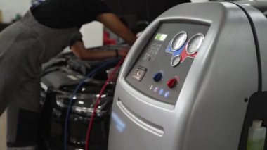Benzin istasyonu ekipmanları klimayı şarj ediyor. Otomatik tamirci araba klima sisteminde soğutucuyu doldurur. Teknisyen havalandırma, araç bakımı, soğutucu yenileme işlemleri yapıyor..