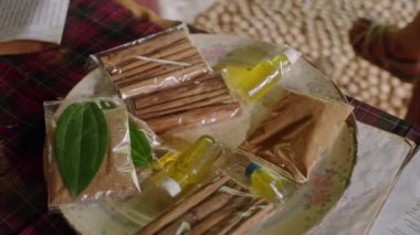 Masada çeşitli tarçın çubukları ve baharatlar sergileniyor, müşteriler açık hava pazarında çeşitli aromatik ürünleri güneşli ortamda satmak için tarıyorlar.