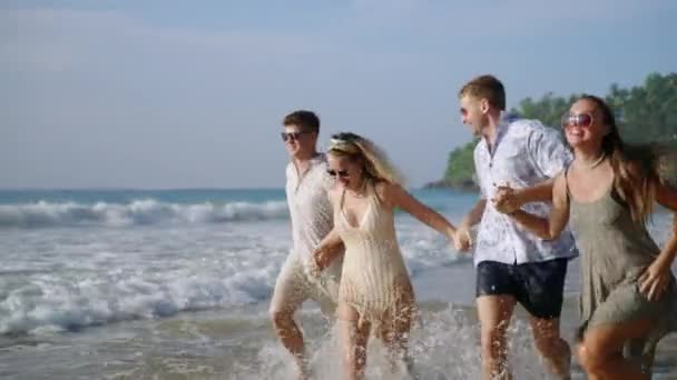 一群群快乐的男人 女人手挽手在阳光灿烂的热带海滩上狂奔 两只快乐的高加索男女情侣在海滨的豪华度假胜地度假时感到寒意 — 图库视频影像