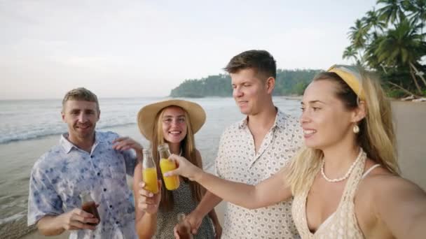 楽しい友人グループ男性 レモネードボトルを持つ女性は カメラのためにポーズ スナップセルフィー 晴れた熱帯の海のビーチで陽気 2人の陽気な慎重なカップルは 海岸で電話で写真を撮る ポピュラービュー — ストック動画