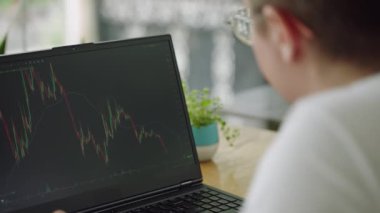 Parlak ofis kurma stratejileri geliştirmek, gerçek zamanlı verileri analiz etmek, aktif ticaret oturumunda alım-satım kararları almak. Odaklanmış piyasa analisti bilgisayar ekranında dalgalanan grafikler üzerinde çalışıyor. Yavaşla