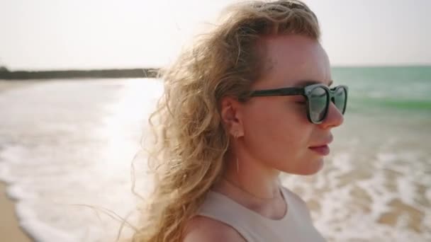 Menina Atraente Óculos Sol Andando Tocando Cabelo Encaracolado Arejado Praia — Vídeo de Stock