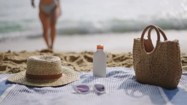 日焼け止めは 夏の余暇と健康を象徴する紫外線に対する皮膚の安全のために適用されます 女性は海から現れ ビーチギアサンブロック 編まれたバッグ 色合いに近づきます スローモーション — ストック動画