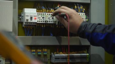 2021-09-23 - Mariupol, Ukrane. Magma fabrikası. Profesyonel elektrikçi, kabinede otomasyon teçhizatını test eder. Devre ve sistem kontrol panelini makineler için kalibre eder..