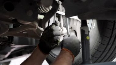 Teknisyen lastik ayarlamak için araç süspansiyonunda aletler kullanır. Otomobil tamircisi servis garajında araba tekerleği hizasını ayarlar. Atölye çalışması, bakım süreci ayrıntılı olarak gösterildi.