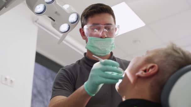 男牙医在现代牙科诊所治疗病人的牙齿 牙科医生在牙科诊所对牙齿进行专业的清洁 医生为男性患者补牙 治疗根管 — 图库视频影像