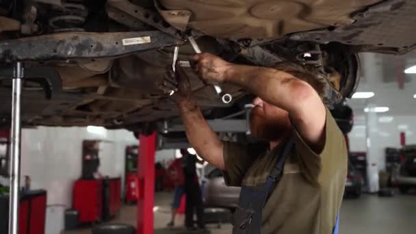 Zkušený Technik Používá Klíč Pod Vozidlem Zaměřuje Upevnění Tlumičů Automechanik — Stock video
