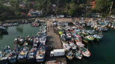 Balıkçılar ağları hazırlar, denize açılmak için hazırlanırlar. Hareketli limanın havadan görüntüsü, canlı balıkçı tekneleri demirli. Sahil köyü, canlı liman manzarası. Sabah güneşi sularda parlıyor..