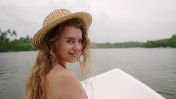 わら帽子をかぶった笑顔の女性は トロピカルな環境を見ながら自然ツアーを楽しんでいます アドベントロウスの女性は 緑豊かな生息地を通じて船舶の航海で川の野生生物を探索しています レジャーリバーボート体験 — ストック動画