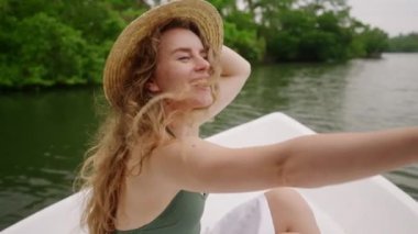 Kollarını açmış, tekneden vahşi hayatı işaret ediyor. Hasır şapkalı heyecanlı bayan gezgin nehir safarisinde kuş izlemekten hoşlanıyor. Doğal yaşam ortamında boş bir yolculuk, eko-turizmin keyfi. Yavaş çekim.