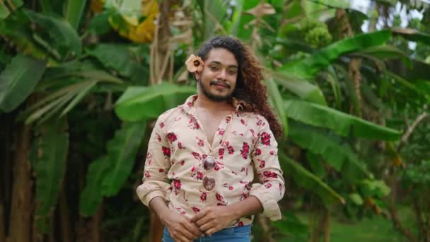 Lgbtqのプライドは 熱帯緑を表しています フランボイアの男性は自信を持って 飾られた花のシャツ 目の接触 髪の花をポーズします エキスプレスなスタンスは多様性を祝います — ストック動画