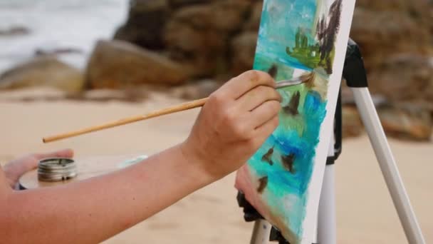 창조적 여성은 브러시 작품을위한 팔레트를 사용합니다 예술가는 모래사장에 경치를 그립니다 — 비디오