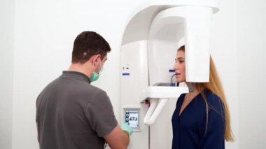 Erkek radyologlar diş röntgeni makinesiyle kadın hastanın diş röntgenini çekiyorlar. Dişçi lazer rehberiyle tarama projeksiyonunu ayarlar. Doktor, dişçi kliniğindeki kadın için röntgen çekiyor..