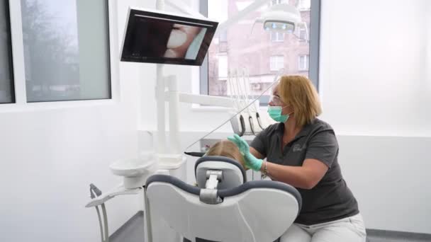 女牙医用口腔内摄像机检查小女孩的牙齿 并在屏幕前观看 在现代牙科诊所 医生用相机检查小孩的牙齿 口腔内摄影机在儿科牙科中的应用 — 图库视频影像