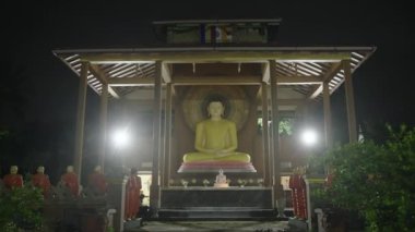 2023-05-05 - Mirissa, Sri Lanka. Tal Aramba Sri Mahendrarama Tapınağı. Tapanlar mumları yakar, barış ve farkındalık için dua ederler. Geceleyin Vesak 'ta Buda heykelini aydınlattı. Geleneksel fenerler asılır.