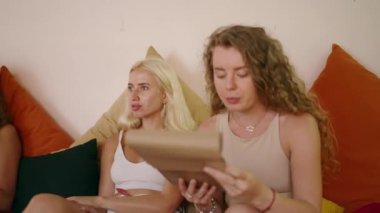 Neşeli kızlar menü okuyor ve hipster tropikal kafede sipariş veriyorlar. Bayan arkadaşlar konuşuyor, restoranda yemek seçiyorlar. Yaz sabahı güzel bir yerde oturan genç kadınlar..